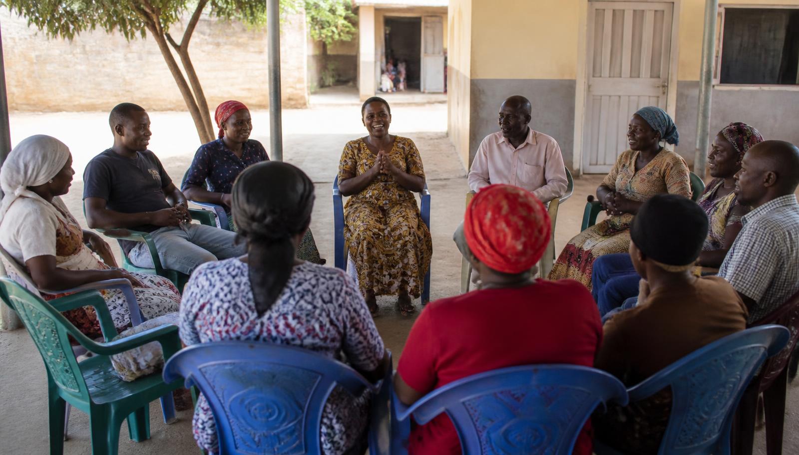 A savings group seated in a circle, talking together during a meeting